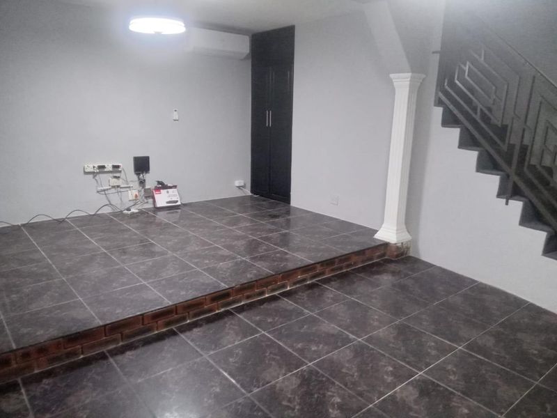 An empty living area featuring a raised tiled platform, built-in storage, and a staircase with metal balustrades.