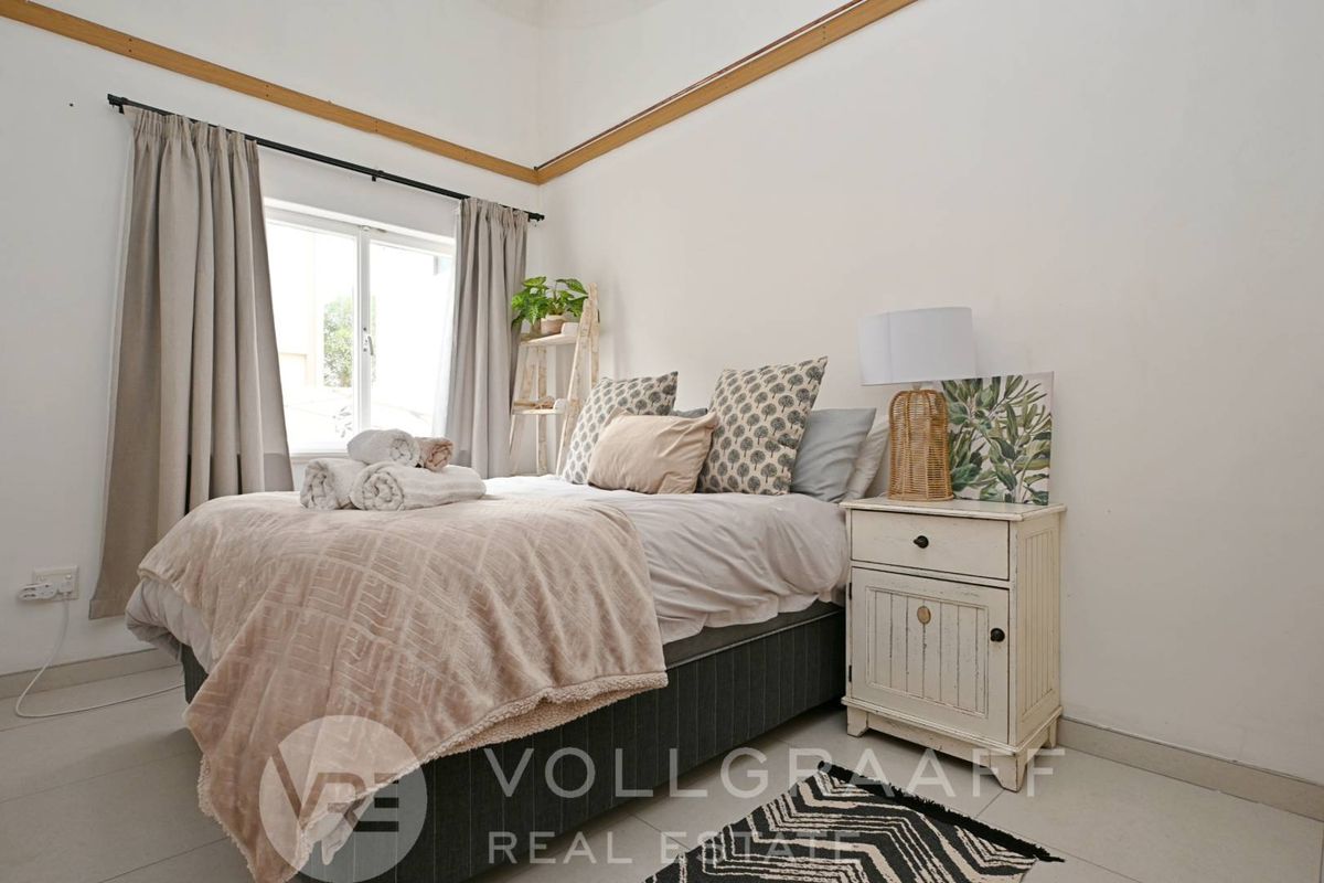 A bright bedroom featuring tiled flooring, neutral walls, and a window with curtain tracks, providing a clean and functional living space.