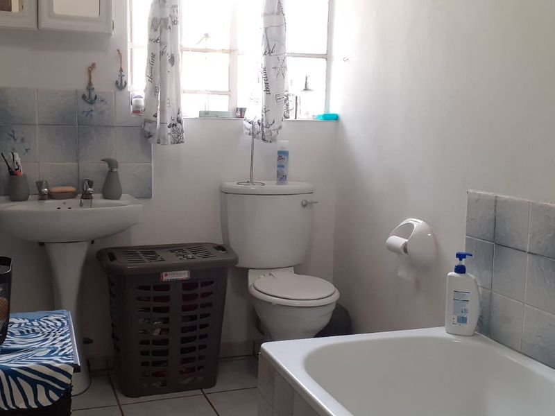 A functional bathroom featuring a pedestal basin, toilet, and bathtub with tiled splashbacks and flooring.