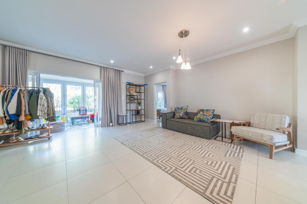 A bright and spacious living area featuring large sliding glass doors that open to an outdoor patio, complemented by modern recessed lighting.