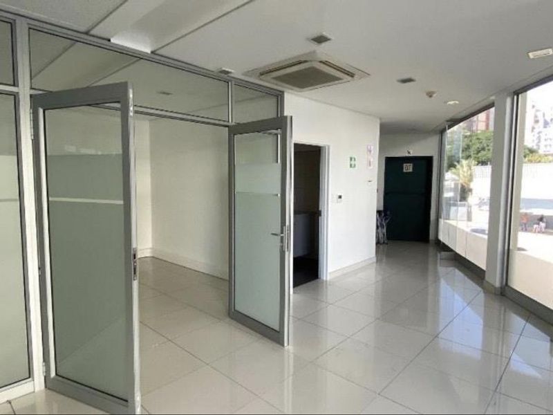 Modern office space featuring aluminum-framed glass partitions, tiled flooring, and large glass windows providing ample natural light.