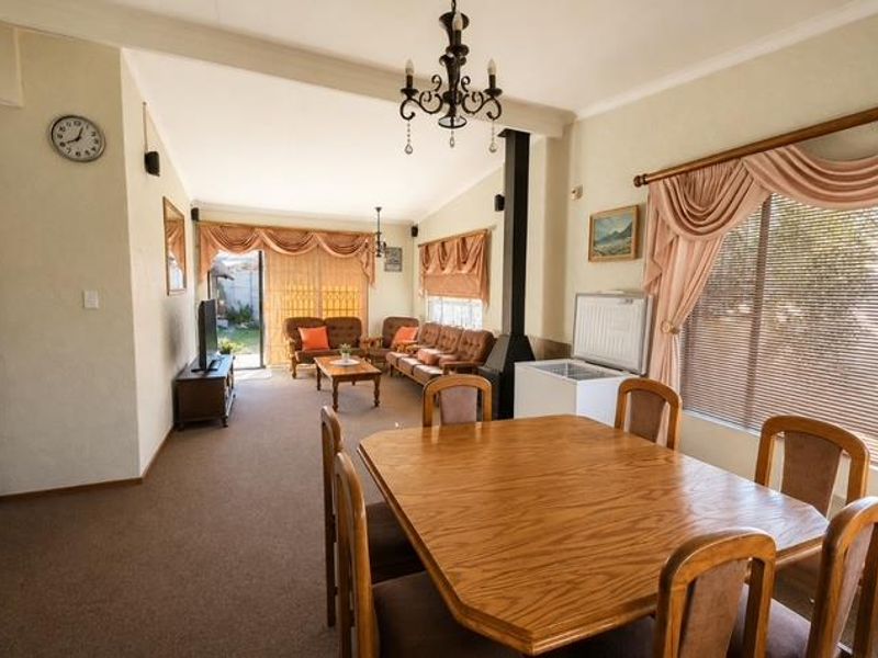 Spacious open-plan living and dining area featuring a fireplace, neutral wall finishes, and large windows with natural light.