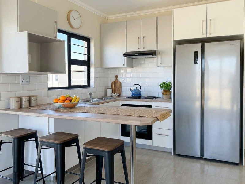 Modern kitchen featuring white cabinetry, subway tile backsplash, integrated appliances, and a functional breakfast bar with a clean, contemporary finish.