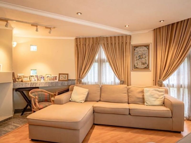 A comfortable living room featuring a built-in fireplace, laminate flooring, and large windows with floor-to-ceiling curtains, providing a warm and inviting atmosphere.