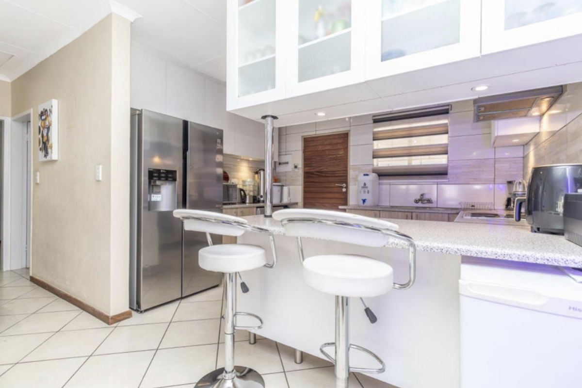 Modern kitchen featuring a breakfast bar, built-in cabinetry, tiled flooring, and integrated lighting, providing a functional and well-lit culinary space.