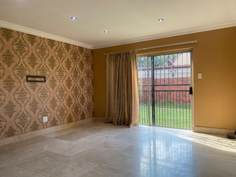 Spacious living room featuring tiled flooring, decorative wallpaper, recessed lighting, and a sliding glass door providing access to the rear garden.
