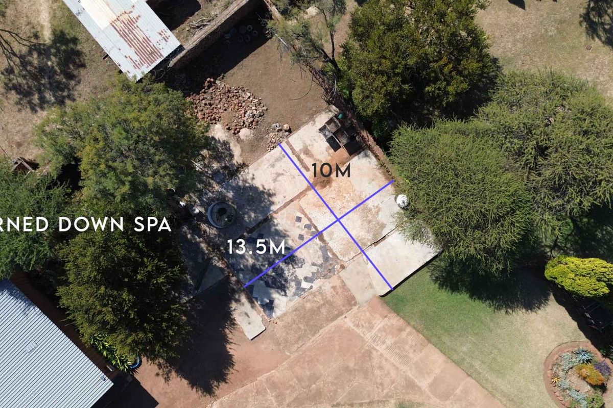 Aerial view of a fire-damaged concrete slab area, measuring 10m by 13.5m, situated within a landscaped property setting.