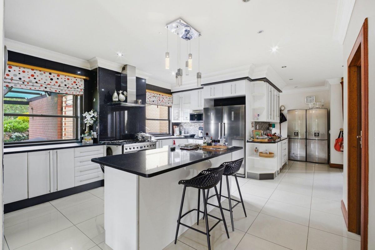 Modern kitchen featuring a central island, granite countertops, white cabinetry, stainless steel appliances, and tiled flooring.