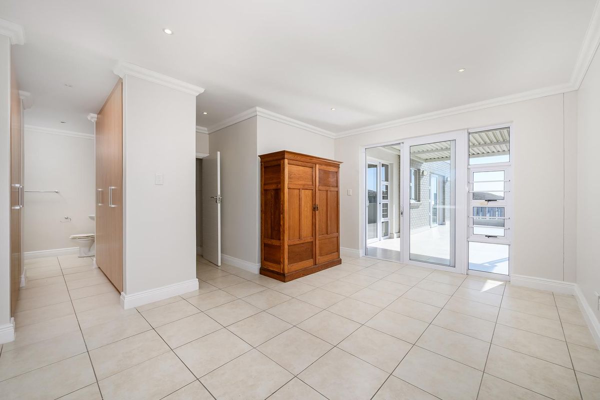 Spacious bedroom featuring tiled flooring, built-in cupboards, recessed lighting, and sliding glass doors providing direct access to an outdoor patio area.