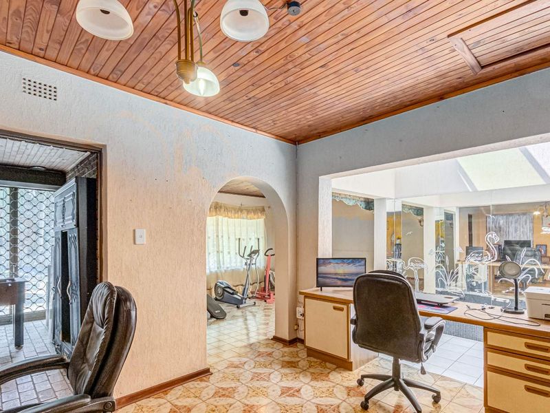 A multi-functional office space featuring a timber-clad ceiling, arched architectural details, and a glass partition wall, offering potential for modern renovation.