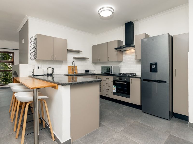 Modern kitchen featuring granite countertops, subway tile backsplash, built-in oven with gas hob, extractor fan, and a convenient breakfast bar.
