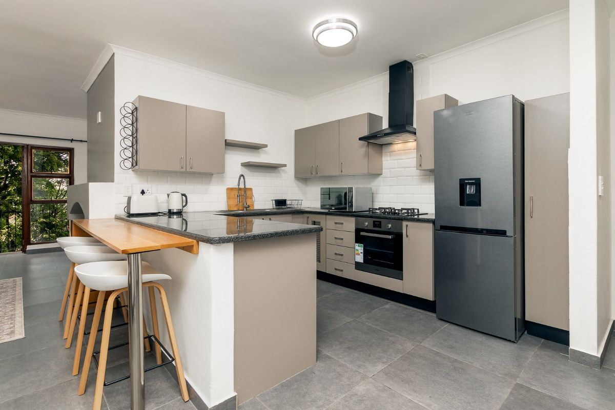 Modern kitchen featuring granite countertops, subway tile backsplash, built-in oven with gas hob, extractor fan, and a convenient breakfast bar.