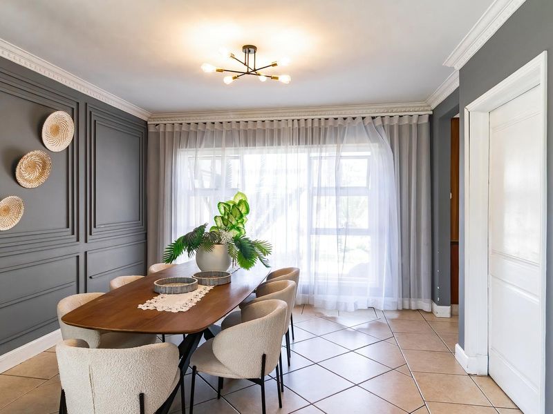 Elegant dining room featuring decorative wainscoting, crown molding, and tiled flooring, creating a sophisticated space for formal meals.