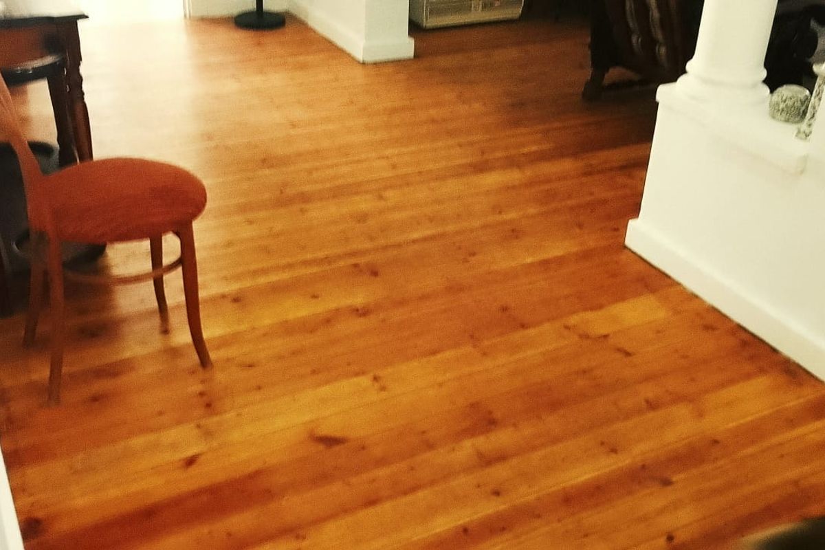 A view of a living area featuring polished wooden flooring and a decorative column.