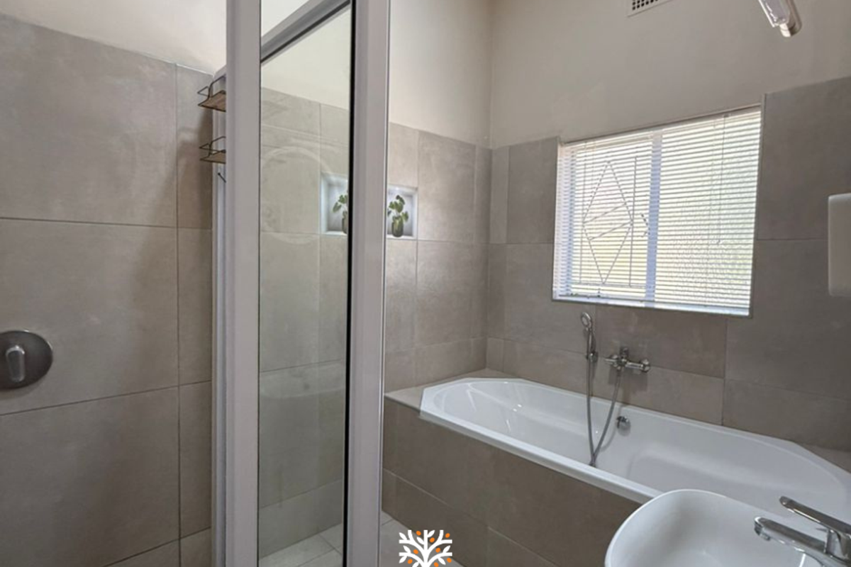 Modern bathroom featuring a tiled shower enclosure, a built-in bathtub with handheld shower mixer, and a wall-mounted basin.