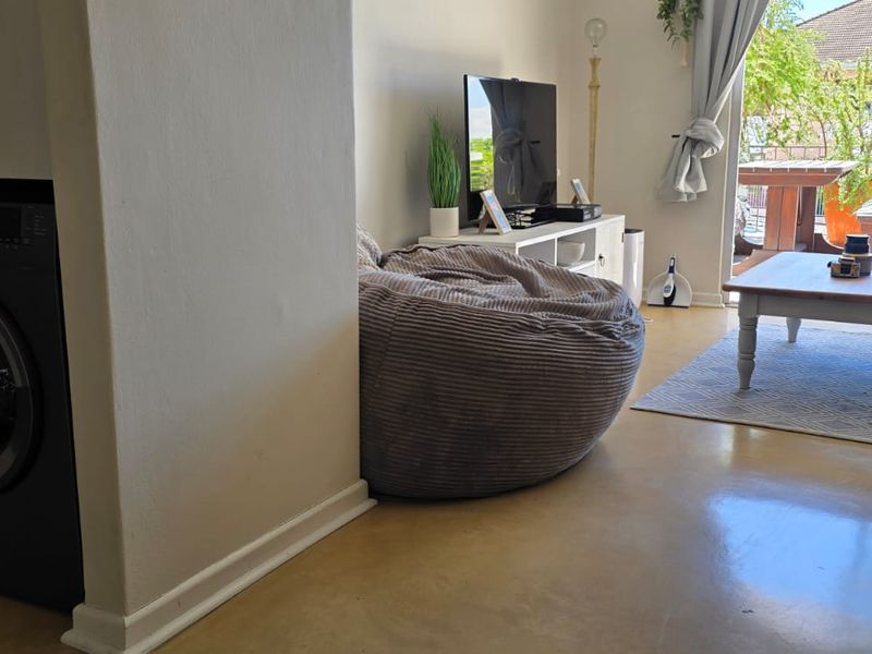 Open plan living area featuring polished concrete floors and a built-in laundry nook, with direct access to an outdoor balcony through sliding glass doors.