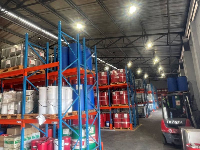 A functional industrial warehouse space featuring extensive steel racking systems, exposed roof trusses, and durable concrete flooring, suitable for storage and logistics operations.
