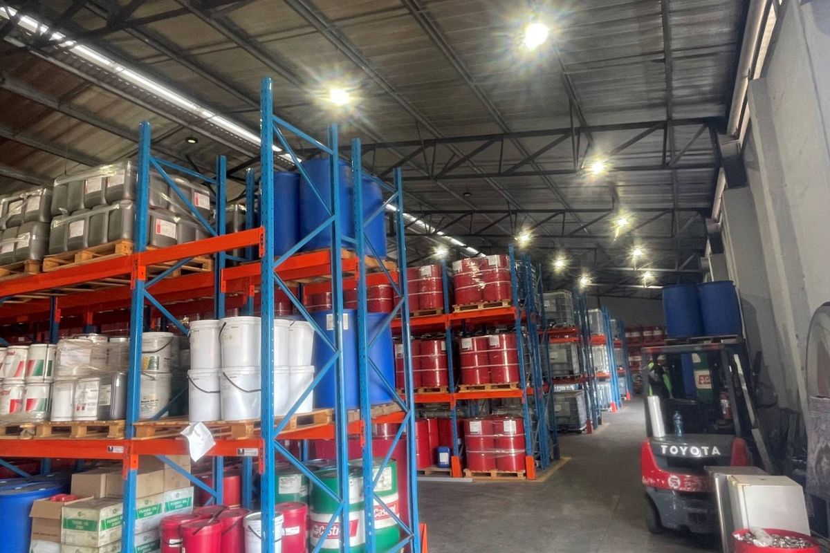 A functional industrial warehouse space featuring extensive steel racking systems, exposed roof trusses, and durable concrete flooring, suitable for storage and logistics operations.
