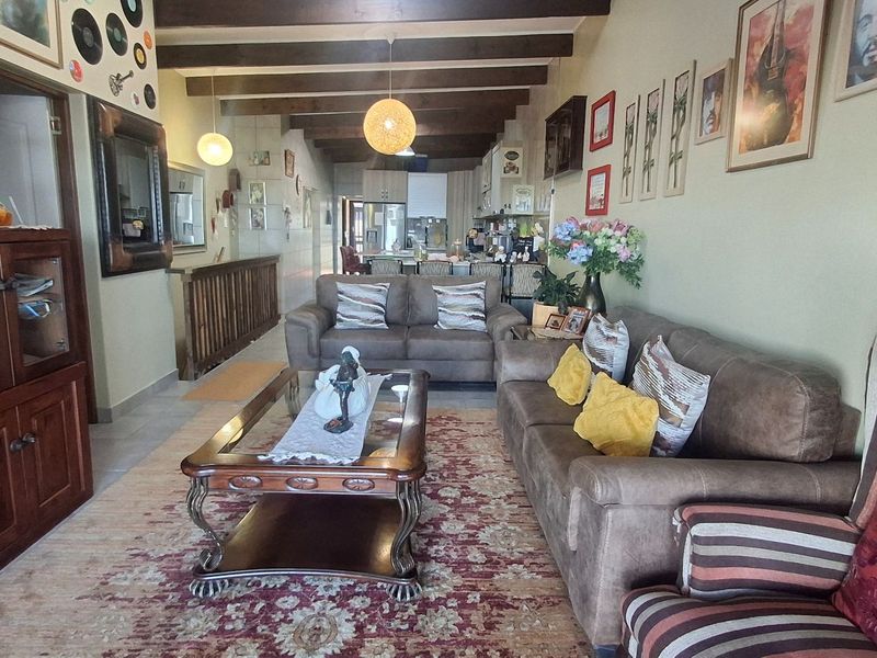 Spacious open-plan living area featuring exposed timber ceiling beams, tiled flooring, and a seamless flow into the kitchen space.