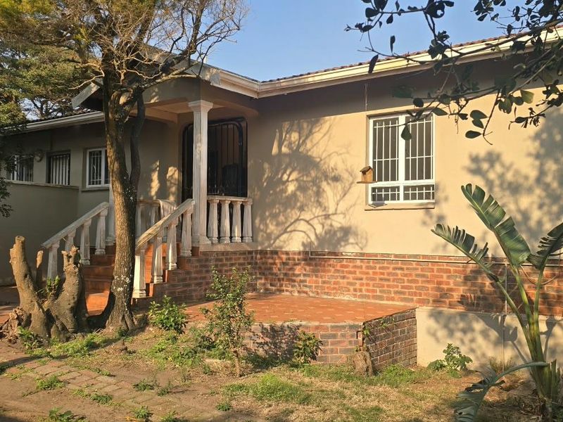 Front exterior view of a single-story house featuring a brick base, tiled entrance steps with concrete balustrades, and security bars on windows.