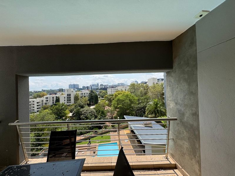 A covered balcony featuring a stainless steel balustrade, tiled flooring, and elevated views overlooking the complex pool and surrounding neighborhood.