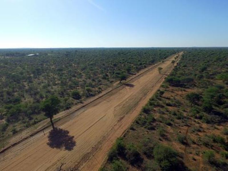 An aerial view of a rural farm property featuring a long dirt access road stretching through the natural landscape.