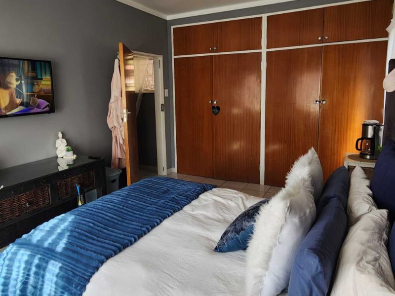 A bedroom featuring built-in wooden cupboards and tiled flooring, providing functional storage space.