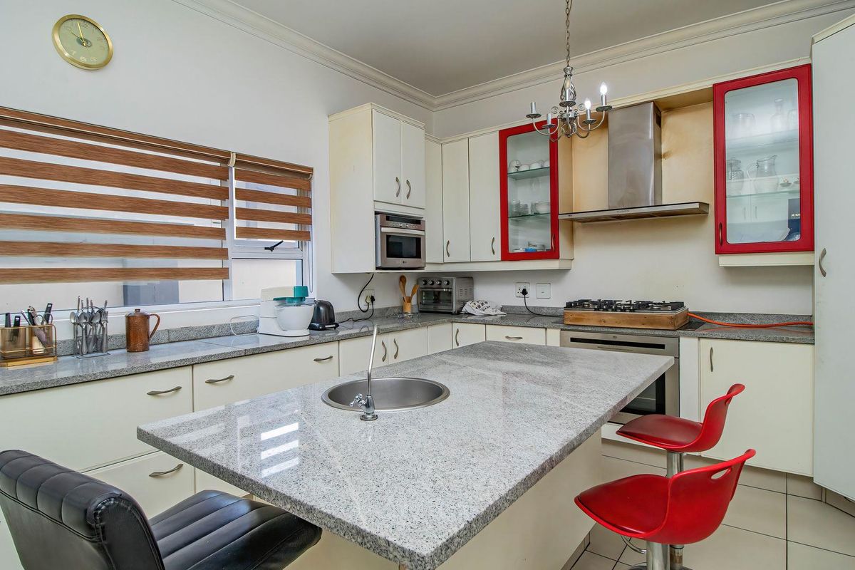 A functional kitchen featuring granite countertops, a central island with a prep sink, built-in oven, gas hob, and ample cabinetry storage.