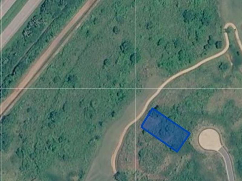 Aerial view of a vacant residential plot of land with surrounding natural vegetation and access road infrastructure.