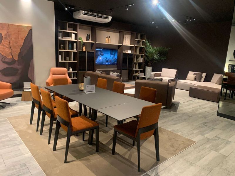 A modern, well-lit open-plan retail showroom space featuring tiled flooring, built-in shelving, and integrated track lighting.