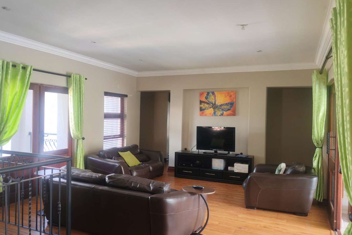 Spacious living room featuring warm wood-look flooring, recessed wall niche for media, and double door access to an outdoor area.
