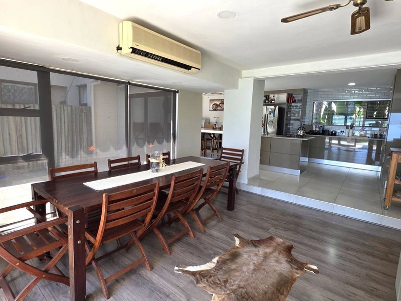 Spacious open-plan living and dining area featuring laminate and tiled flooring, integrated kitchen with subway tile backsplash, and direct access to outdoor space.