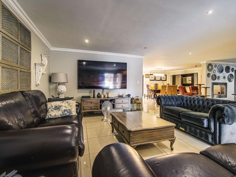 Spacious open-plan living area featuring tiled flooring, recessed downlighting, and a fireplace, seamlessly connecting the lounge and dining spaces.