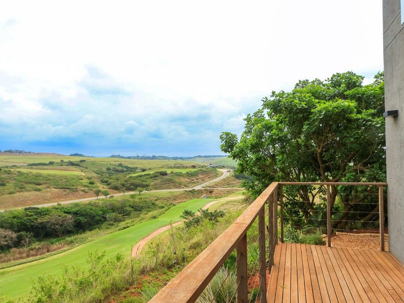 A timber balcony featuring wire balustrades, offering expansive views over the surrounding golf course and natural landscape.