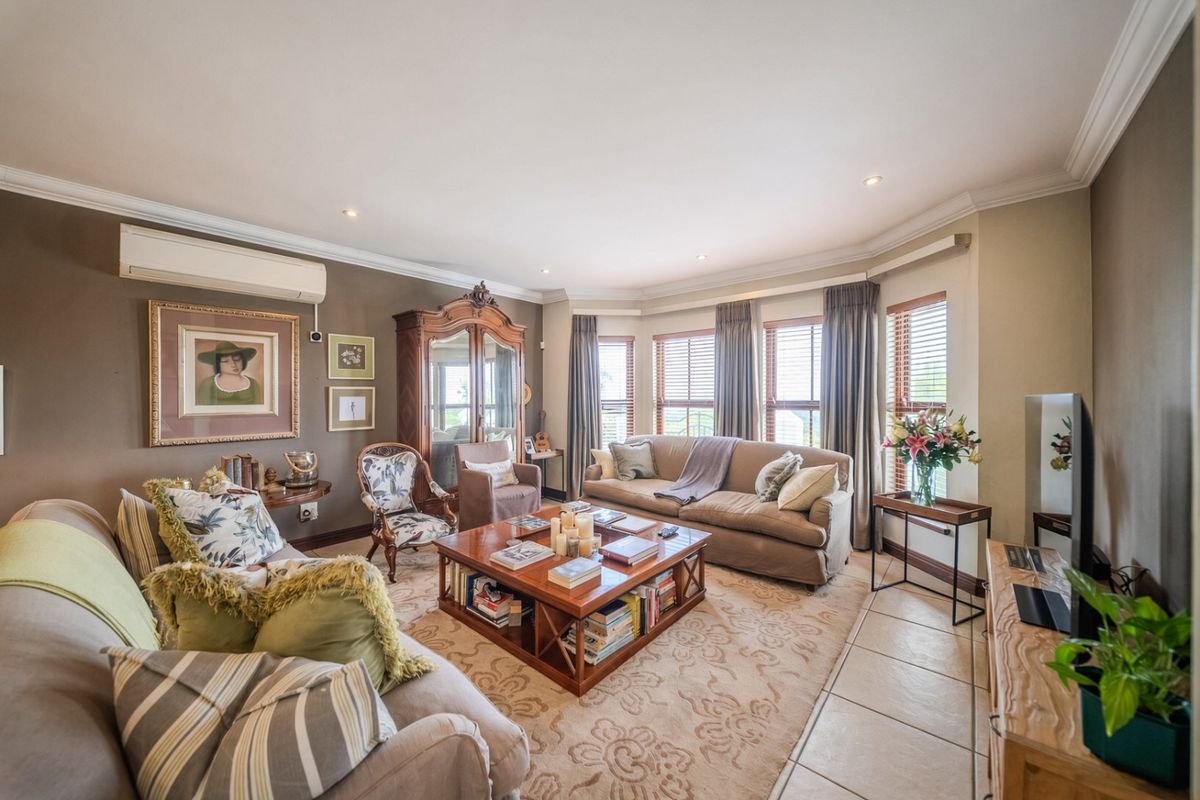 Spacious living room featuring a large bay window, tiled flooring, recessed downlighting, and a wall-mounted split-system air conditioning unit.