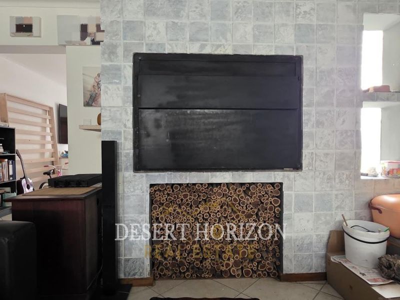 Living room featuring a prominent built-in fireplace with a tiled surround and integrated log storage compartment.