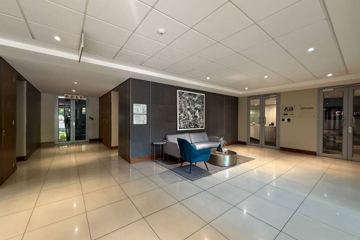 Modern office building entrance lobby featuring polished tiled flooring, a suspended ceiling with recessed lighting, and secure glass access doors.
