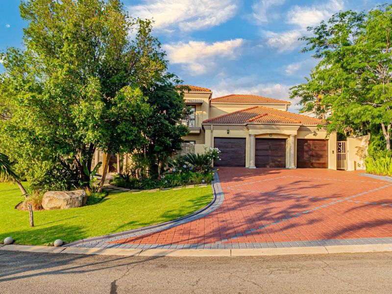 A well-maintained residential property featuring a triple garage, paved driveway, and established front garden with mature trees.