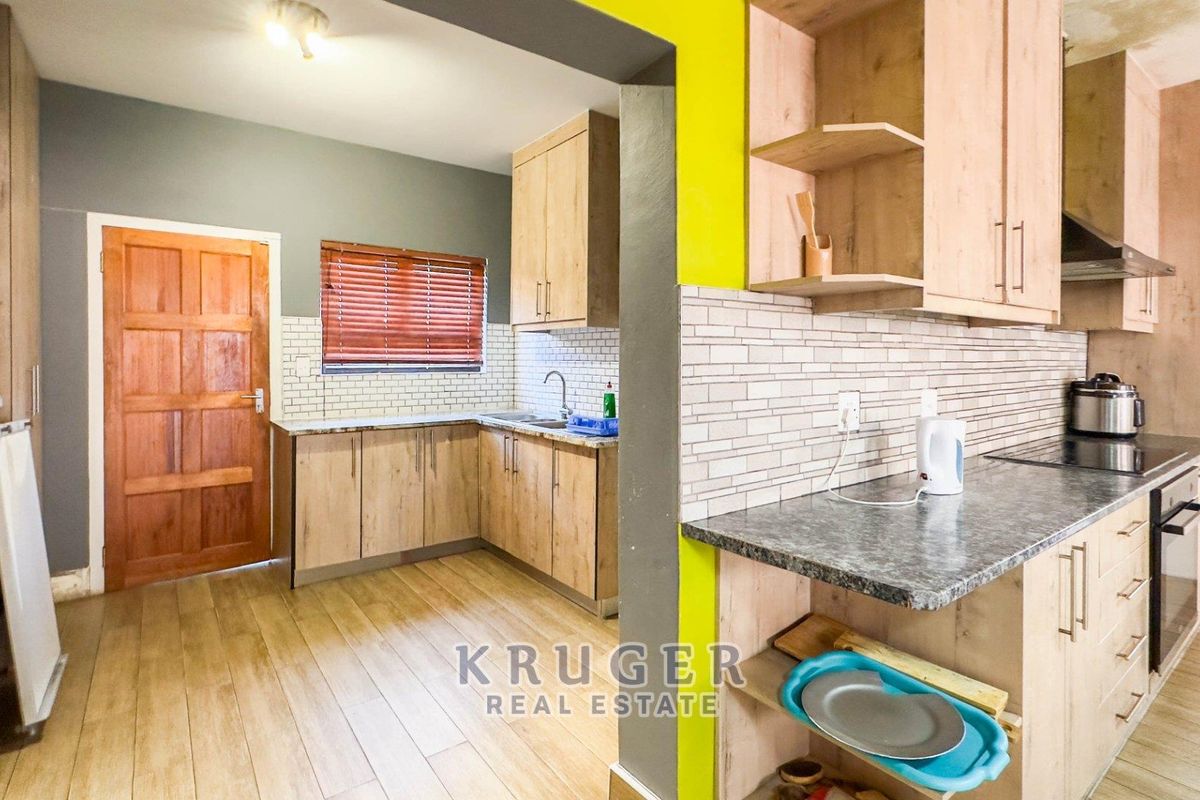 A functional kitchen featuring light wood cabinetry, granite-look countertops, subway tile backsplash, and integrated cooking appliances with a connected prep area.