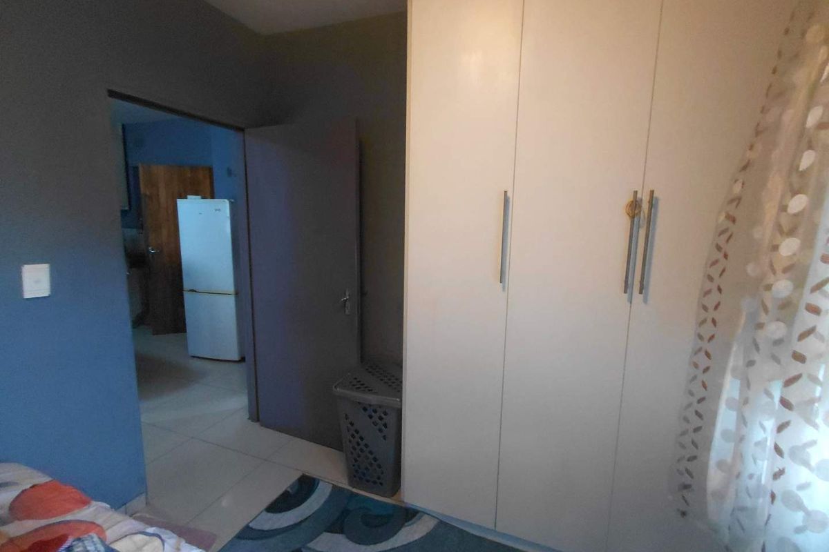 A bedroom featuring built-in floor-to-ceiling wardrobes with modern handles, providing ample storage space and direct access to the adjacent living area.