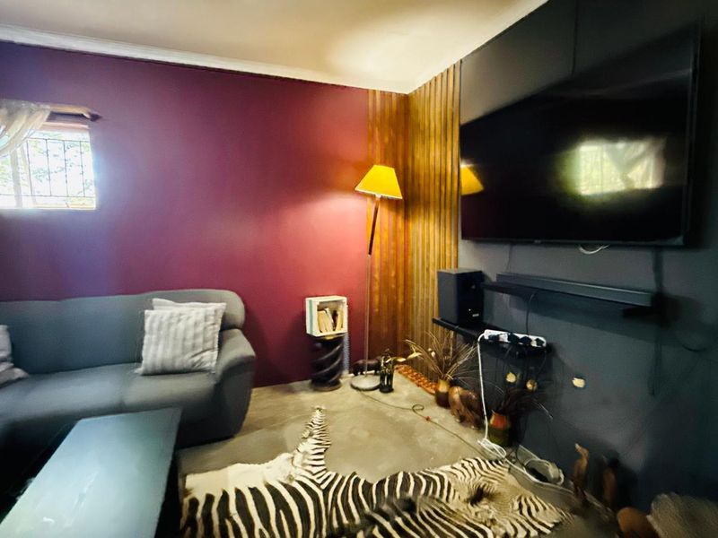 A living room featuring a bold purple accent wall, timber slat paneling, and polished concrete flooring.