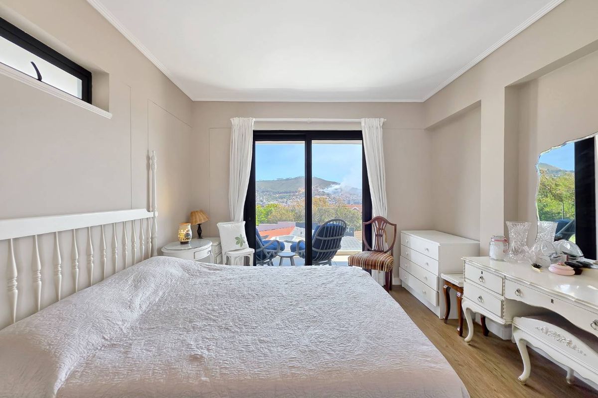 Spacious bedroom featuring laminate flooring, neutral walls, and large sliding glass doors providing access to a balcony with scenic views.