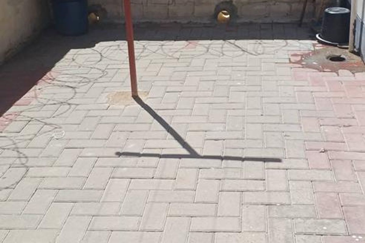 A paved rear courtyard area featuring a perimeter wall with security razor wire and a fixed washing line.