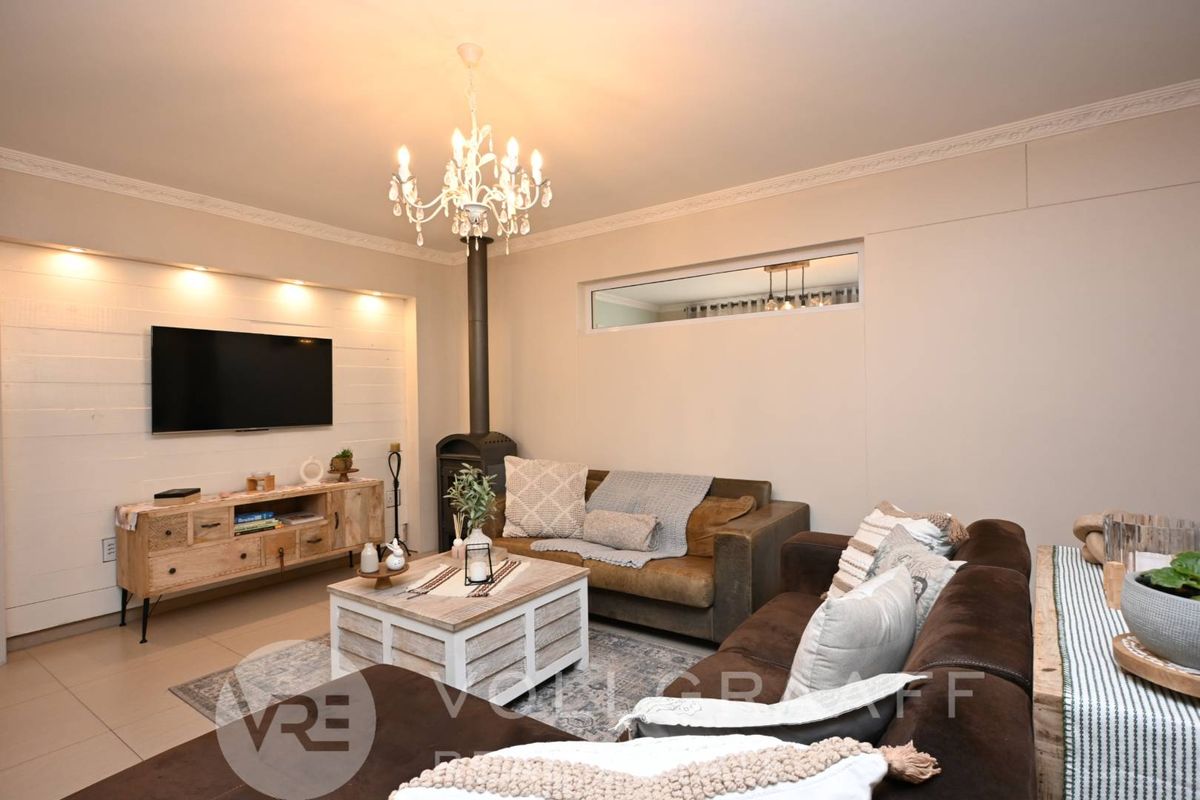 A cozy living room featuring a wood-burning fireplace, recessed wall lighting, and decorative crown molding.