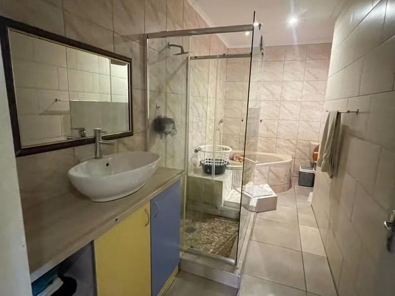 A functional bathroom featuring a vessel sink vanity, a glass-enclosed shower, and a built-in bathtub with neutral wall and floor tiling.