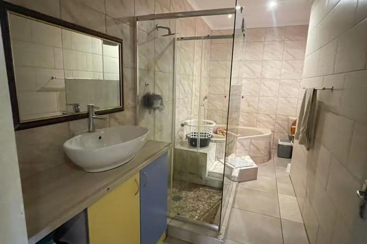 A functional bathroom featuring a vessel sink vanity, a glass-enclosed shower, and a built-in bathtub with neutral wall and floor tiling.