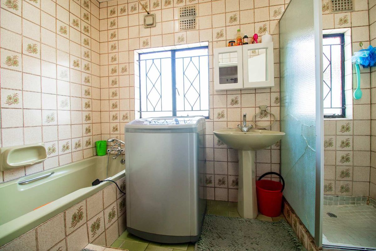 A dated bathroom featuring a bathtub, pedestal basin, and a separate shower enclosure with a cracked glass screen.