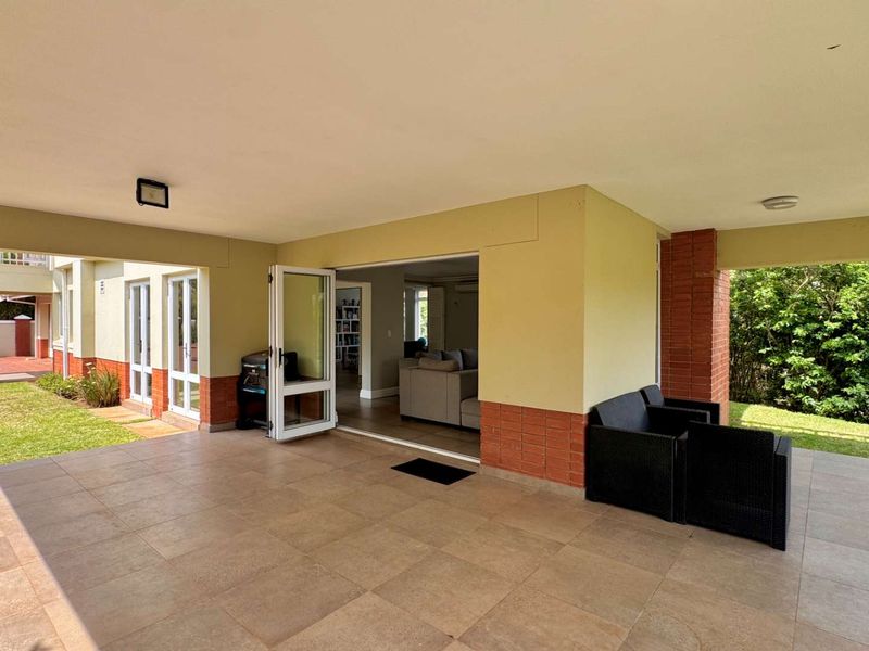 Spacious covered patio featuring tiled flooring and exposed brick pillars, providing seamless indoor-outdoor flow through bi-fold doors to the garden area.