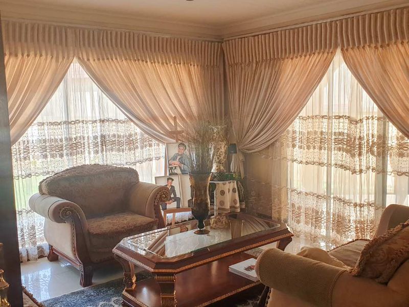A living room featuring tiled flooring, recessed ceiling lighting, and large sliding glass doors with floor-to-ceiling curtains.