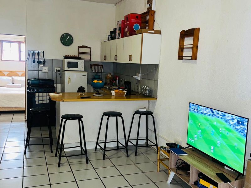 Open plan living and kitchen area featuring tiled flooring, functional cabinetry, and a breakfast bar counter, providing a practical layout for daily living.